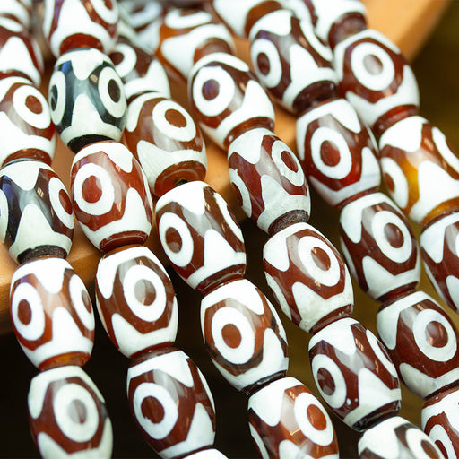 This is a Dakota Stones 10x14mm DZI Agate Red Eye Gemstone strand with barrel beads in 15-16 inch strand.