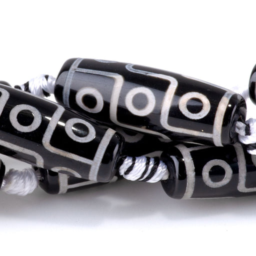 This is a Dakota Stones 10x30mm DZI Agate Nine Eye Black Gemstone strand with barrel beads in 15-16 inch strand.