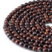 This is a Dakota Stones 6mm Red Tiger Eye Large Hole Gemstone strand with round beads in 8 inch strand.