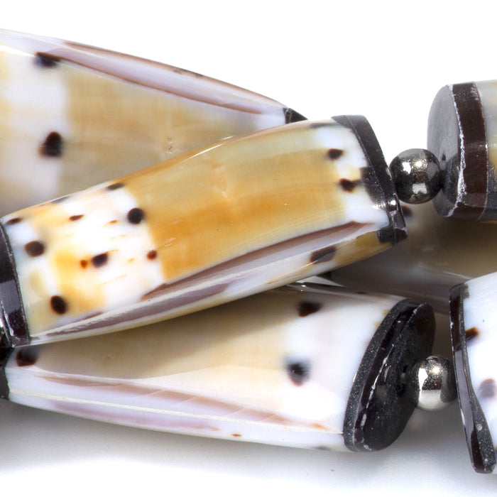 This is a Dakota Stones 15x28mm Conus Capitaneus Shell Puff Rectangle Gemstone strand of round beads in 15-16 inch strand.